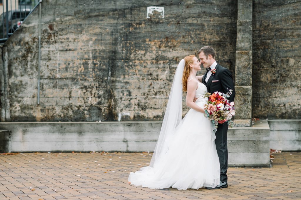Bride and Groom in front of stone wall at rainy fall wedding in Louisville KY